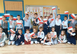 Dzieci stoją do wspólnego zdjęcia z flagami Polski